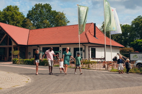 Familia paseando frente a una casa de vacaciones en Camping de Papillon, parque en Overijssel, Países Bajos.