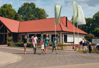 Gezin op weg bij een vakantiewoning op Camping de Papillon vakantiepark in Overijssel, Nederland.