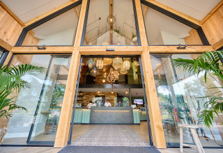 Ingang van Camping de Papillon vakantiepark in Overijssel, Nederland, met glazen deuren en groene planten.