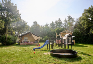 Speelplaats en glampingtenten op Camping de Papillon in Overijssel, Nederland, omgeven door natuur.