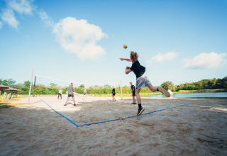 Mensen spelen beachvolleybal op het zand bij Camping de Papillon, een vakantiepark in Overijssel, Nederland.