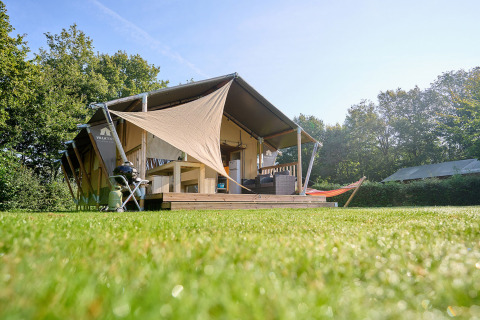 Tienda glamping con terraza y hamaca en Camping de Papillon, parque vacacional en Overijssel, Países Bajos.