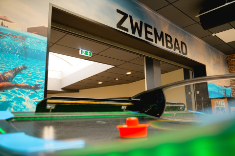 Zwembad ingang bij Camping de Schatberg, Limburg, Nederland, met zicht op een airhockeytafel dichtbij.