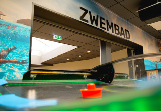Zwembad ingang bij Camping de Schatberg, Limburg, Nederland, met zicht op een airhockeytafel dichtbij.