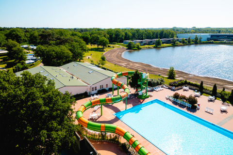 Vista aérea de Camping de Schatberg en Limburg, Países Bajos, con piscina, tobogán y lago en verano.