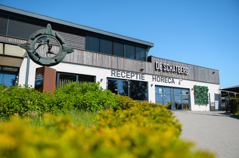 Entrada al parque vacacional Camping de Schatberg en Limburgo, Países Bajos, con letreros de recepción y horeca.
