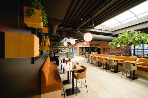 Modern restaurant interior with plants, stylish seating and bright lighting at Camping de Schatberg, Limburg, Netherlands.