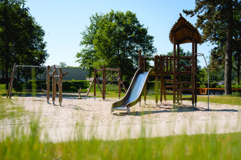 Parque infantil con columpios, tobogán y torre de escalada en Camping de Schatberg, Limburg, Países Bajos.