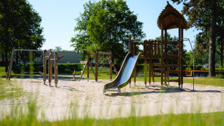 Parque infantil con columpios, tobogán y torre de escalada en Camping de Schatberg, Limburg, Países Bajos.