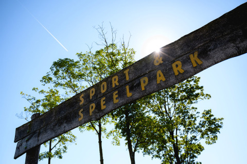 Wooden sign reading 'Sport & Speelpark' at Camping de Schatberg holiday park in Limburg, Netherlands, sunny day.