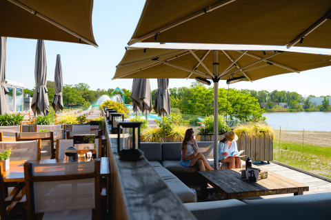 Outdoor seating at Camping de Schatberg, Limburg, Netherlands, overlooking a lake and green scenery.