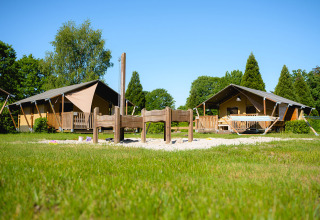 Twee glampingtenten en een speelzandbak bij Camping de Schatberg, vakantiepark in Limburg, Nederland.