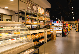 Supermarkt bij Camping de Schatberg, Limburg, Nederland met vers brood, gebak en moderne rekken.