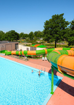 Piscina exterior y toboganes de colores en Camping de Schatberg, parque vacacional en Limburgo, Países Bajos.