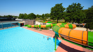 Piscina exterior y toboganes de colores en Camping de Schatberg, parque vacacional en Limburgo, Países Bajos.