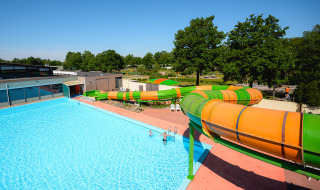 Piscina exterior y toboganes de colores en Camping de Schatberg, parque vacacional en Limburgo, Países Bajos.