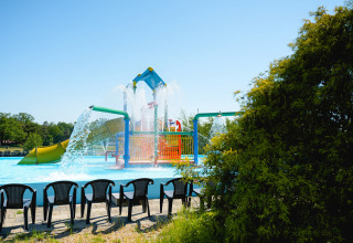 Waterspeeltuin met glijbanen, fonteintjes en lege stoelen op Camping de Schatberg in Limburg.