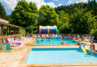 Outdoor swimming pool at Camping de Vaubarlet in Auvergne-Rhône-Alpes, France, with families enjoying the sun.