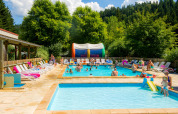Piscina all'aperto a Camping de Vaubarlet in Alvernia-Rodano-Alpi, Francia, con famiglie che si divertono.