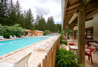 Udendørs swimmingpool med liggestole og siddeområde ved Camping de Vaubarlet i Auvergne-Rhône-Alpes, Frankrig.
