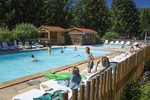 Personas nadando y descansando junto a la piscina en Camping de Vaubarlet, un parque vacacional en Auvergne-Rhône-Alpes, Francia.