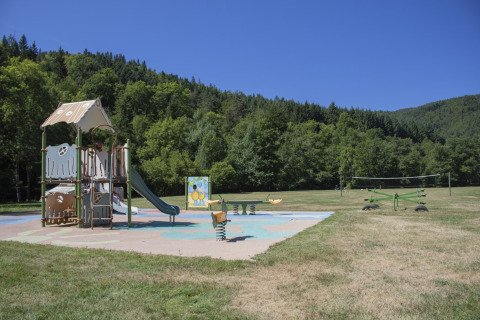 Parco giochi al Camping de Vaubarlet con scivolo e giochi, immerso nel verde in Alvernia-Rodano-Alpi, Francia.