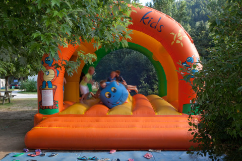 Niños jugando en un castillo inflable colorido en Camping de Vaubarlet en Auvergne-Rhône-Alpes, Francia.