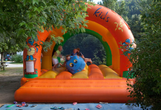 Bambini che giocano su un castello gonfiabile colorato al Camping de Vaubarlet in Auvergne-Rhône-Alpes, Francia.