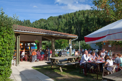 Huéspedes disfrutan de comidas al aire libre en Camping de Vaubarlet, un parque vacacional en Auvergne-Rhône-Alpes.