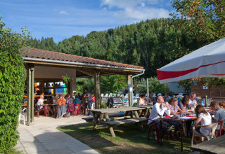 Vakantiegangers genieten van eten in open lucht bij Camping de Vaubarlet, een park in Auvergne-Rhône-Alpes.
