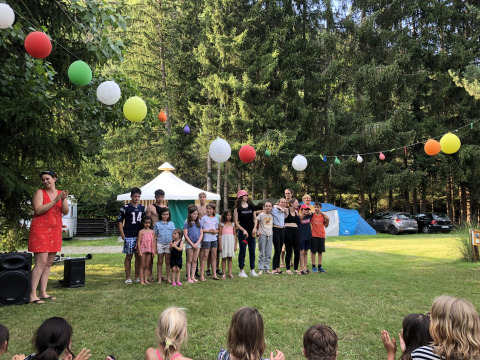 Bambini e adulti festeggiano all’aperto sotto lanterne colorate al Camping de Vaubarlet in Francia.