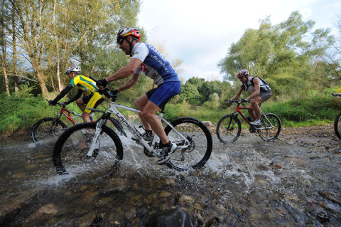 Ciclisti attraversano un ruscello in mountain bike vicino al Camping de Vaubarlet in Auvergne-Rhône-Alpes, Francia.