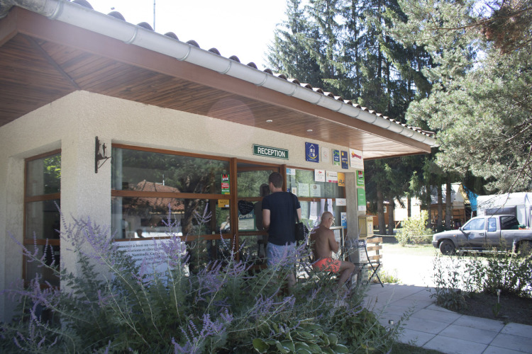 Reception at Camping de Vaubarlet, a holiday park in Auvergne-Rhône-Alpes, France, with people outside.