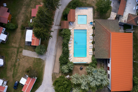 Aerial view of Camping de Vaubarlet with swimming pools, red-roofed buildings and paths in Auvergne-Rhône-Alpes, France.