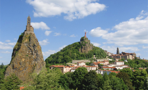 Blick auf Vulkanklippen und historische Bauten bei Camping de Vaubarlet in Auvergne-Rhône-Alpes, Frankreich.