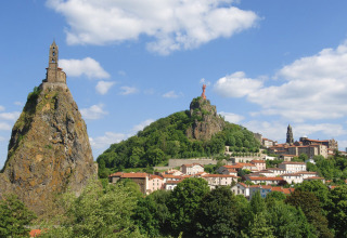 Blick auf Vulkanklippen und historische Bauten bei Camping de Vaubarlet in Auvergne-Rhône-Alpes, Frankreich.