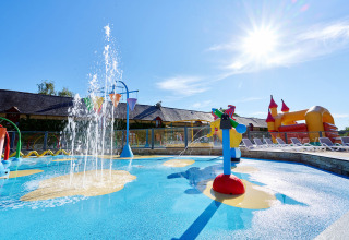 Area giochi d’acqua per bambini con fontane, lettini e castello gonfiabile al Domaine du Logis in Bretagna, Francia.