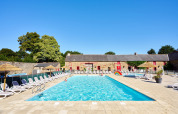 Udendørs swimmingpool med liggestole på Camping Domaine du Logis i Bretagne, Frankrig, under klar himmel.
