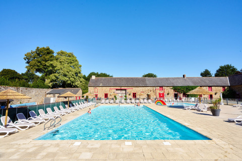 Piscina al aire libre con tumbonas en Camping Domaine du Logis en Bretaña, Francia, bajo cielo azul despejado.