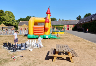 Bambini giocano a scacchi e si divertono sul castello gonfiabile al Camping Domaine du Logis in Bretagna, Francia.
