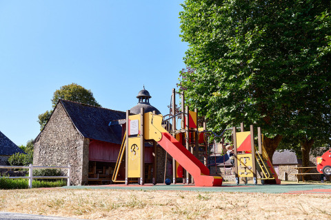 Speeltuin met glijbaan en bomen bij Camping Domaine du Logis vakantiepark in Bretagne, Frankrijk.