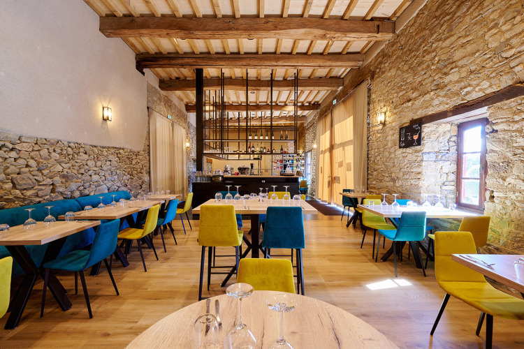 Restaurantbereich mit bunten Stühlen und Steinwänden im Camping Domaine du Logis, Bretagne, Frankreich.