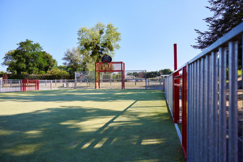 Campo sportivo all'aperto con canestro da basket al Camping Domaine du Logis, situato in Bretagna, Francia.