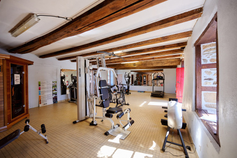 Gimnasio con máquinas y luz solar en Camping Domaine du Logis, un parque vacacional en Bretaña, Francia.