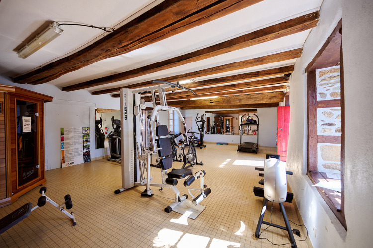 Fitnessraum mit Geräten im Sonnenlicht bei Camping Domaine du Logis, einem Ferienpark in der Bretagne.