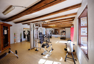 Fitnessrum med træningsmaskiner og sollys, set på Camping Domaine du Logis i Bretagne, Frankrig.