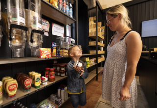Een vrouw en een jongen winkelen samen in een winkel op Camping Domaine du Logis in Bretagne, Frankrijk.