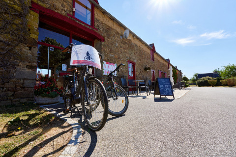 Cykler står foran en stenbygning på Camping Domaine du Logis i Bretagne, Frankrig, en solrig dag.