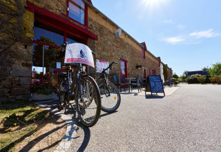 Cykler står foran en stenbygning på Camping Domaine du Logis i Bretagne, Frankrig, en solrig dag.