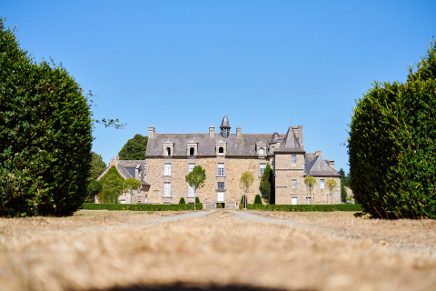 Viale con siepi che conduce a un castello al Camping Domaine du Logis, villaggio vacanze in Bretagna, Francia.